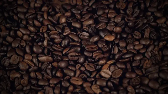 Material de banco: granos de café cayendo, en plano macro.